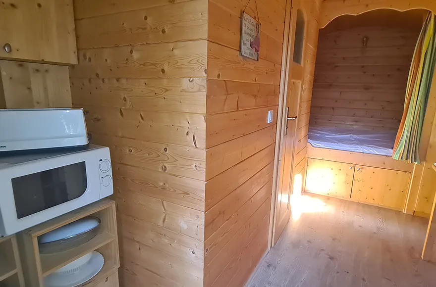 Chambre et coin cuisine de la roulotte, hébergement insolite en Gironde du camping Vendays Montalivet