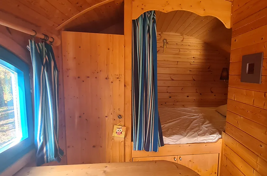 Chambre et coin repas de la roulotte, hébergement insolite en Gironde du camping Vendays Montalivet