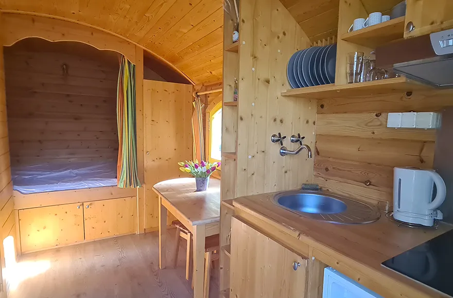Chambre, coin repas et coin cuisine de la roulotte, hébergement insolite en Gironde du camping Vendays Montalivet