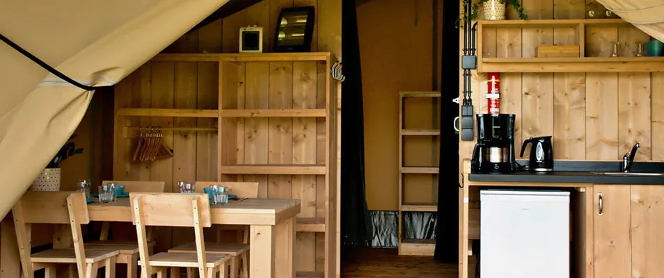 Coin cuisine et coin repas de la tente lodge Safari, hébergement insolite en Gironde du camping Vendays Montalivet